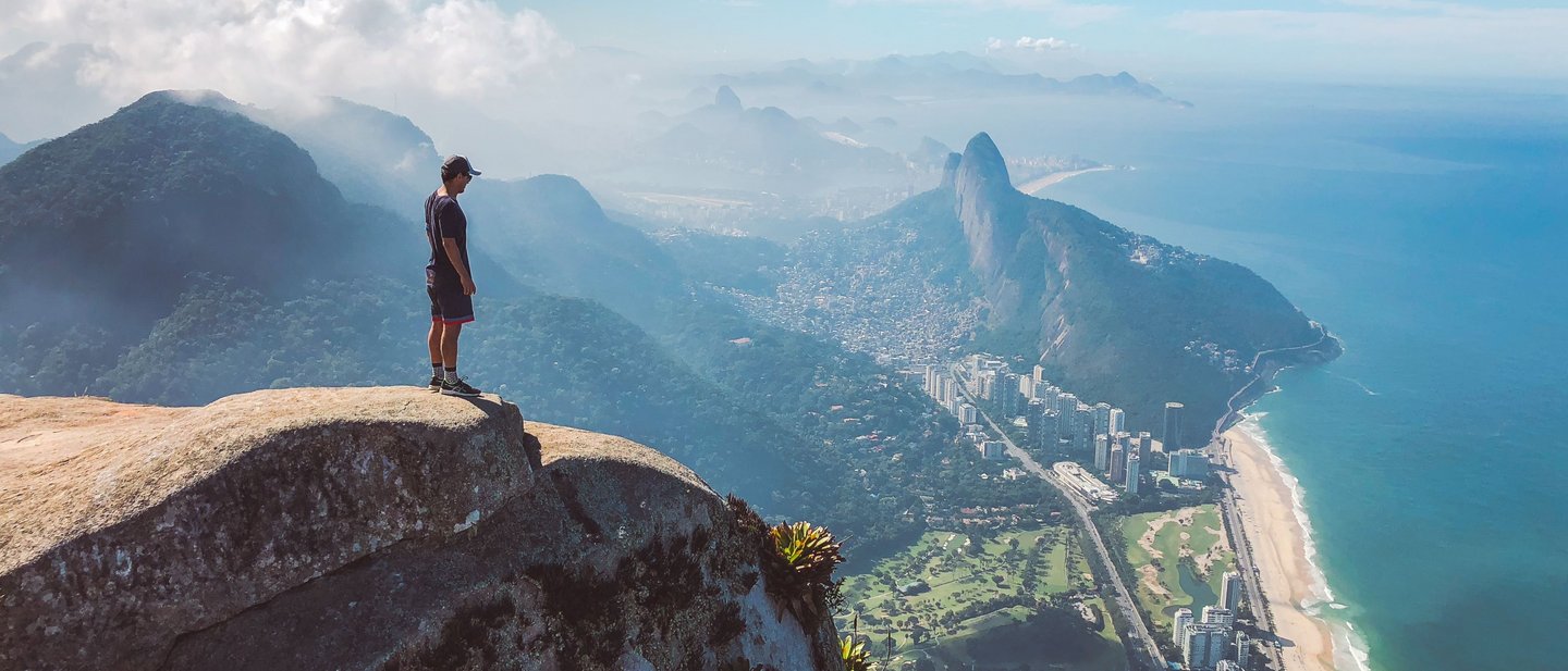 A man stands on the top of Pedra da Gávea watching the views over Rio de Janeiro, Brazil