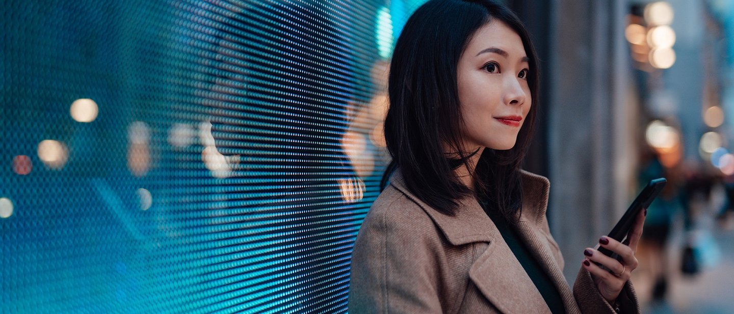 Woman with a mobile phone in front of a digital wall