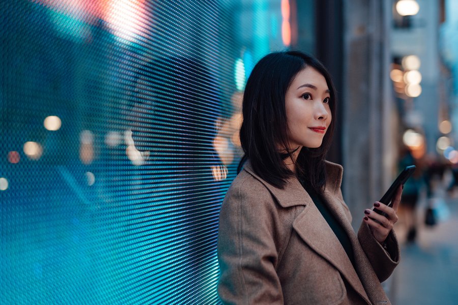 Woman with a mobile phone in front of a digital wall