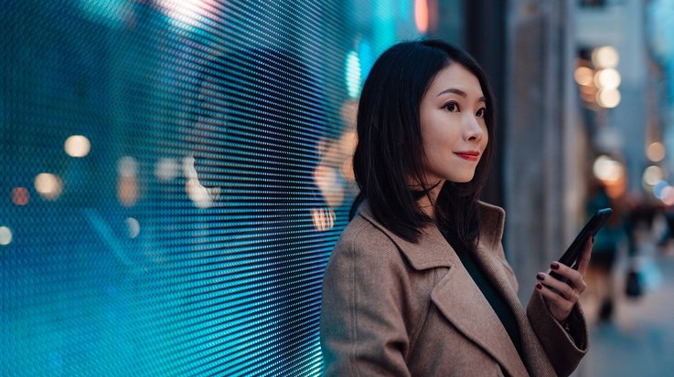 Woman with a mobile phone in front of a digital wall