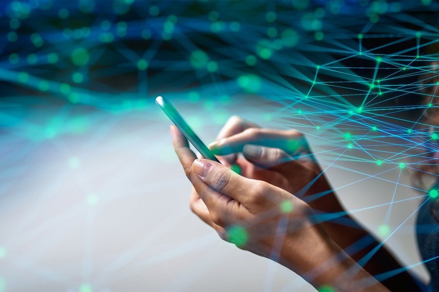 A woman operates a smartphone, above which lies a simulated digital network with many nodes