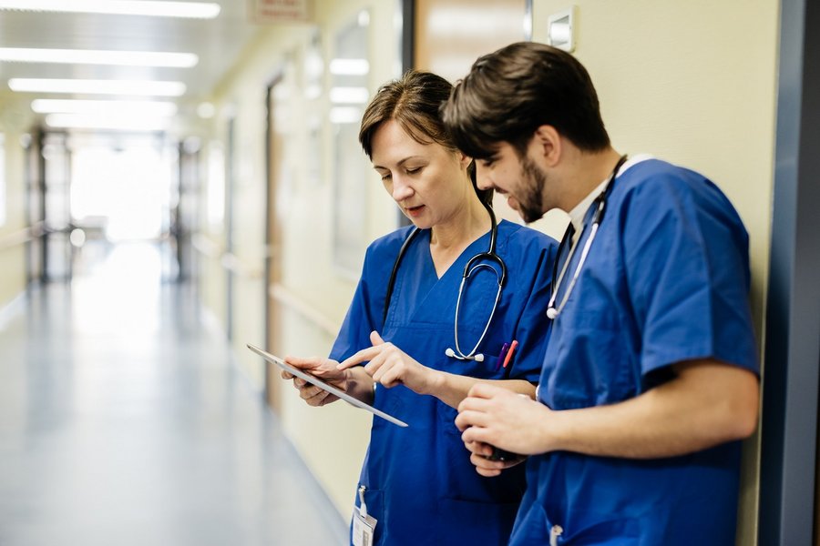 Two medical staff look at a tablet in a medical setting.
