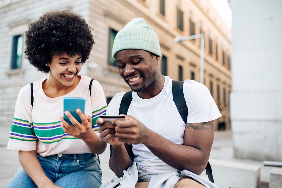 A young couple having a mobile phone and a credit card in their hands