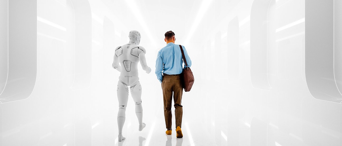 A man in business attire walks alongside a humanoid robot down a brightly lit, futuristic corridor.