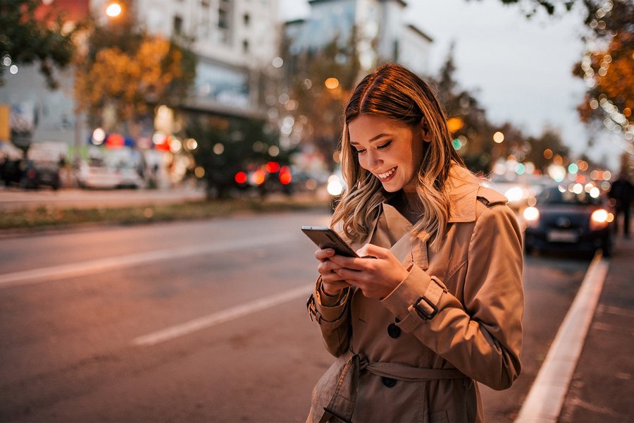 Woman looks at smartphone as evening falls on a metropolitan street.
