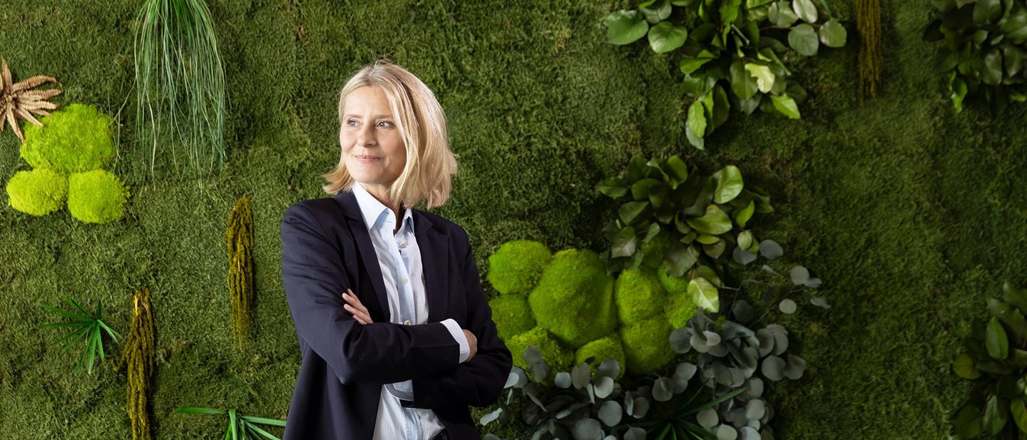 Woman in front of a green plant wall