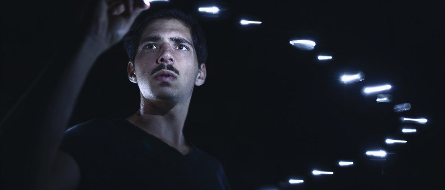 Man surrounded by floating silver bars plucks one from the air with black background