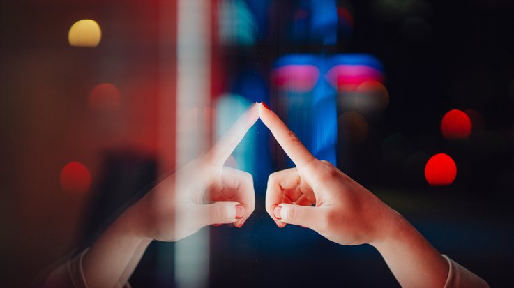 Person touching a surface with city lights reflecting