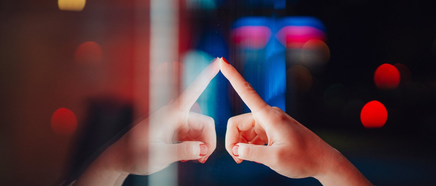 Person touching a surface with city lights reflecting