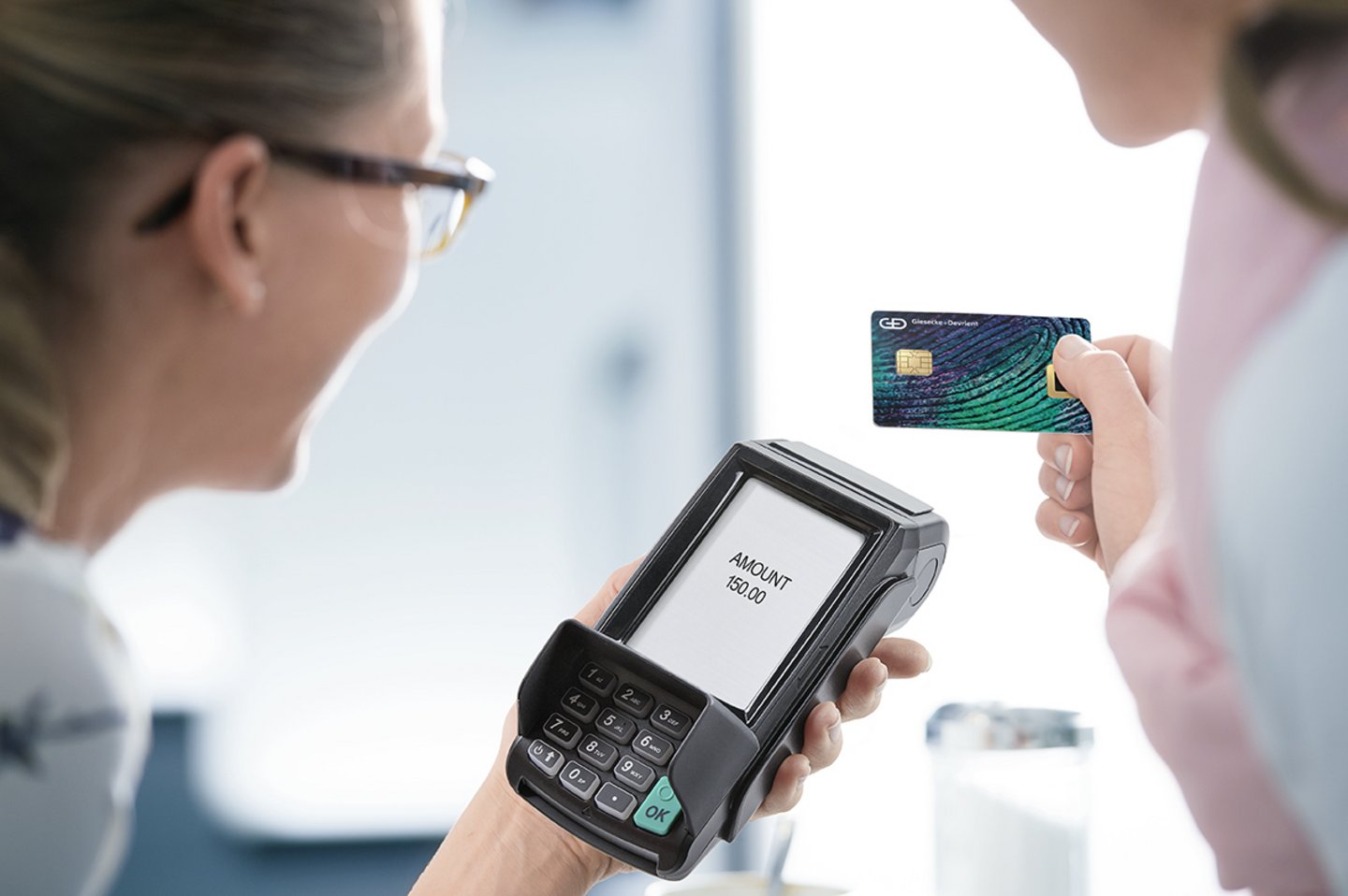 Woman using G+D biometric payment card for payment at a POS