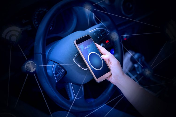 A man has a mobile in his hand which is connected with his car