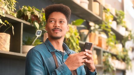 A young man holding a smartphone in a plant shop