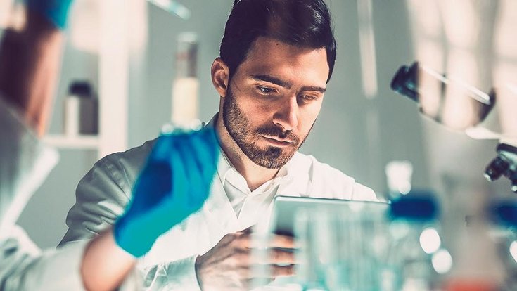 A man in a medical laboratory operates a tablet
