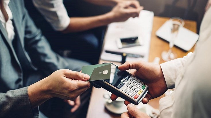 A businessman pays contactless with his credit card in a restaurant