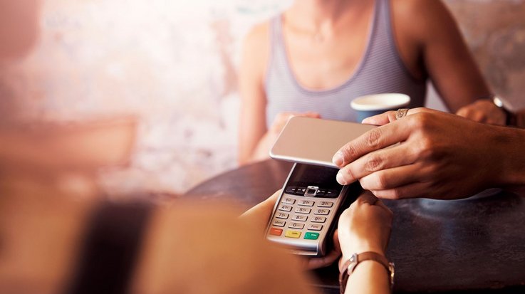 A person pays contactless with the smartphone in a café
