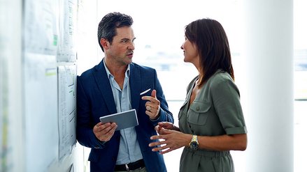 A colleague and a female colleague stand together in the office and lively discuss
