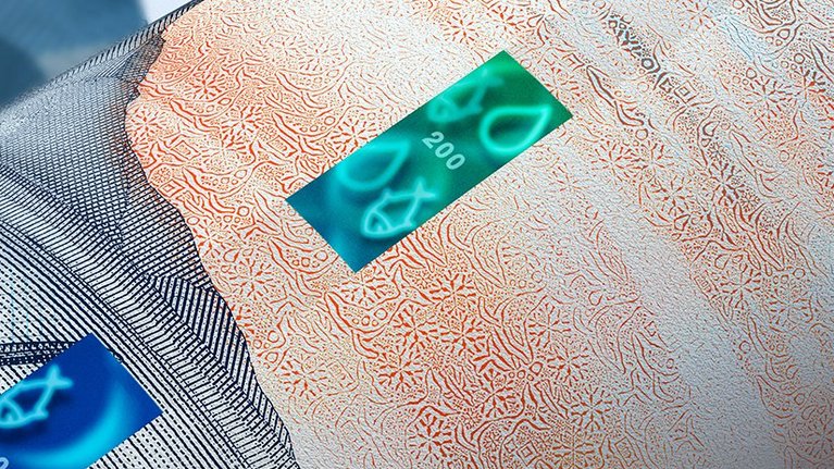 Close up of a sample note with a security thread in blue-green with fishes