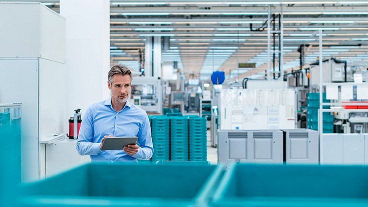 A man with a tablet documents something in a production hall