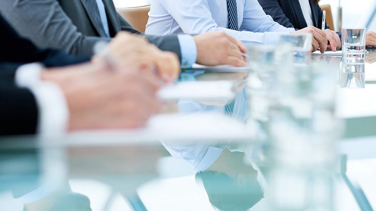four people sitting at a table and taking notes