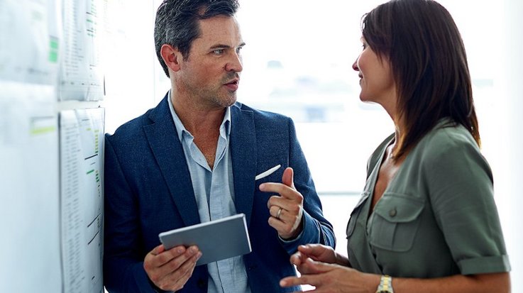 A colleague and a female colleague stand together in the office and lively discuss