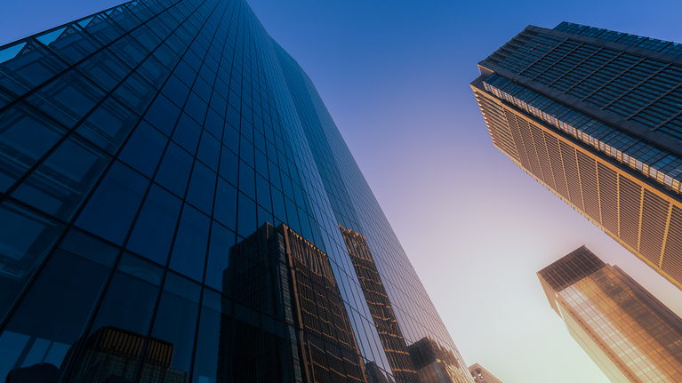 Low-angle view of modern glass skyscrapers at sunset