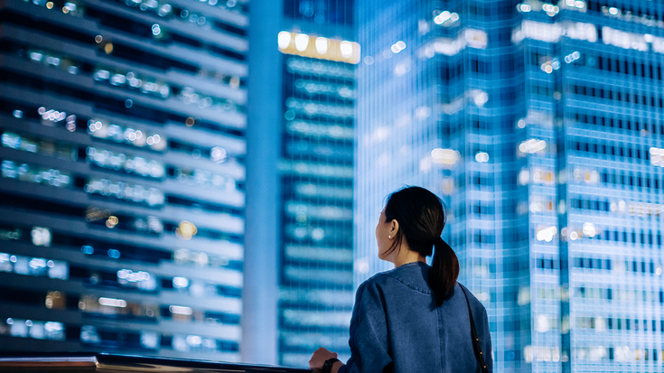 Woman looking at city skyline with tall buildings at night