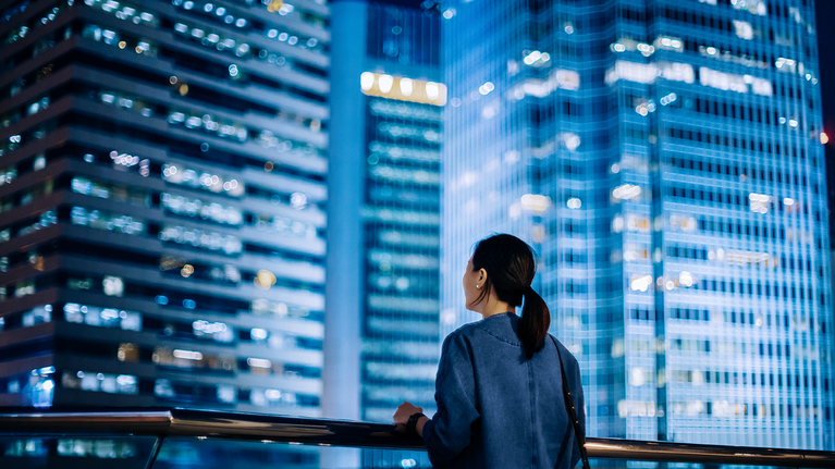 Woman looking at city skyline with tall buildings at night