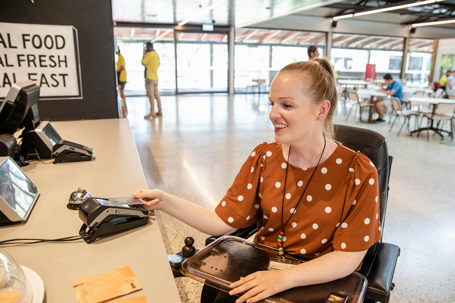 A woman in a wheelchair is paying with her card
