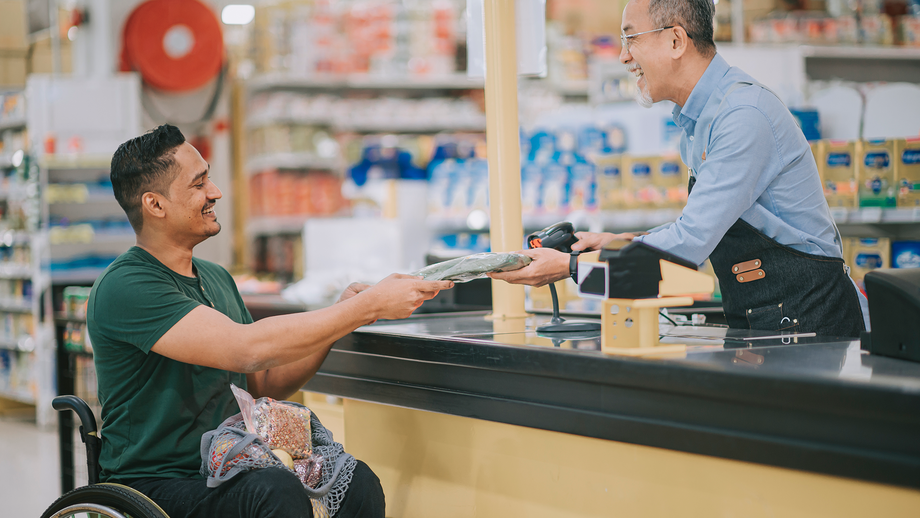 A man in a wheelchair talking to the cashier