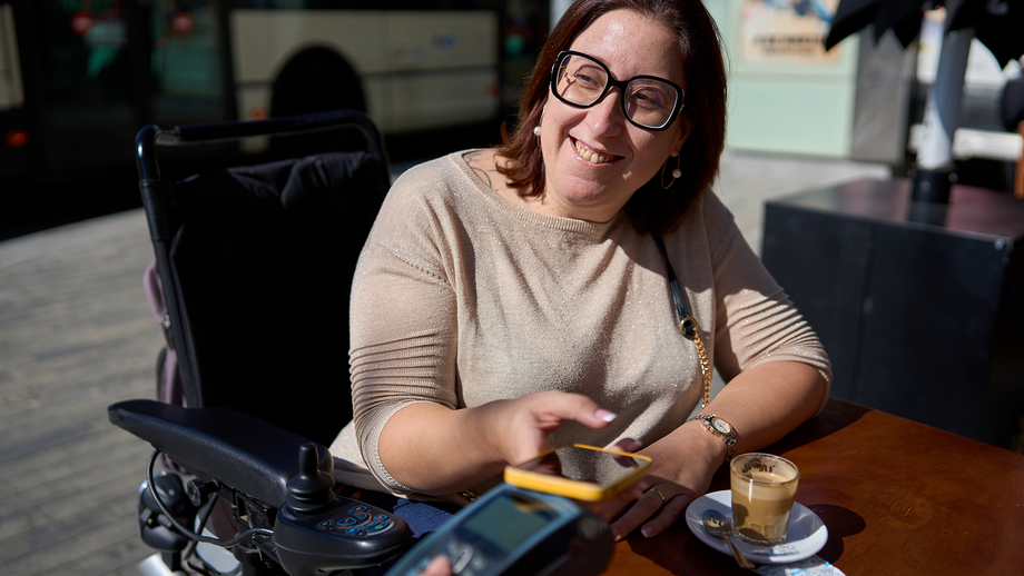 A woman in a wheelchair is paying with her phone