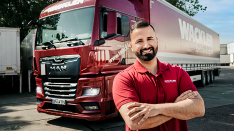 Person in a red shirt standing in front of a red WACKLER truck
