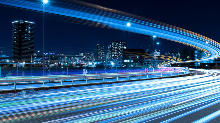 Image of a big city with light trails running through the streets
